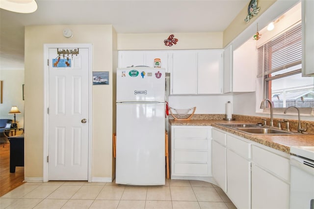 kitchen with white cabinetry, sink, light tile patterned floors, and white refrigerator