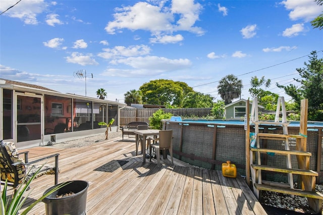 wooden deck with a sunroom and a fenced in pool