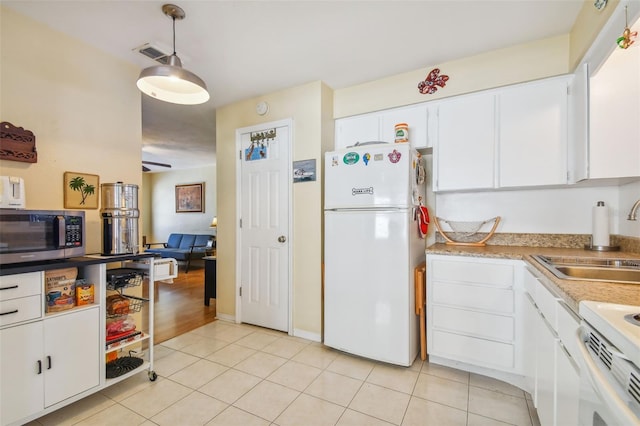 kitchen with sink, light tile patterned floors, decorative light fixtures, white cabinets, and white fridge