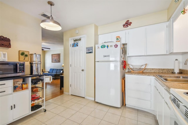 6220 5th Ave S, Saint Petersburg, FL 33707 - kitchen with stainless steel microwave, white cabinets, freestanding refrigerator, and a sink