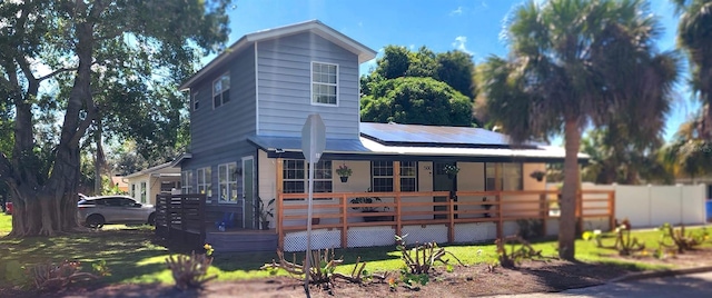 view of front of home featuring covered porch, solar panels, and a deck