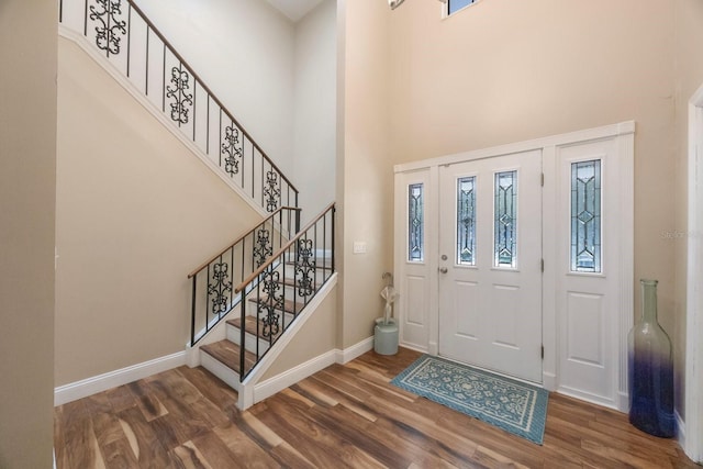 entryway featuring dark wood-type flooring and a towering ceiling