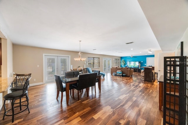 dining room featuring ceiling fan with notable chandelier, wood-type flooring, and french doors