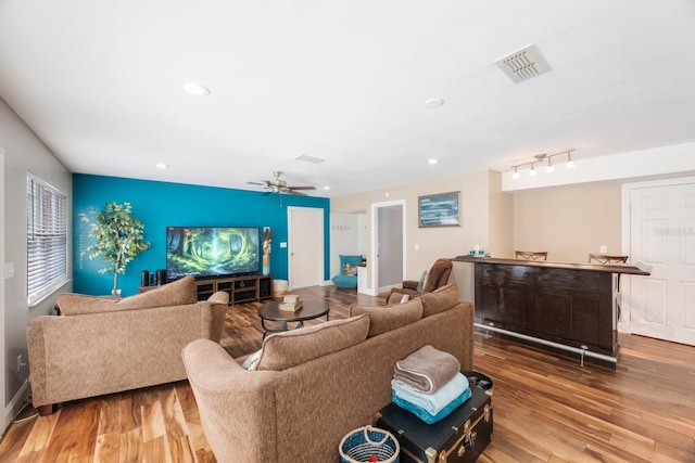 living room with visible vents, wood finished floors, recessed lighting, and an accent wall