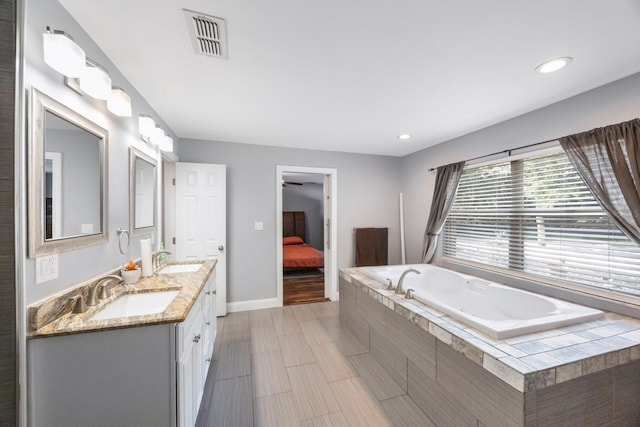 bathroom featuring vanity and tiled bath