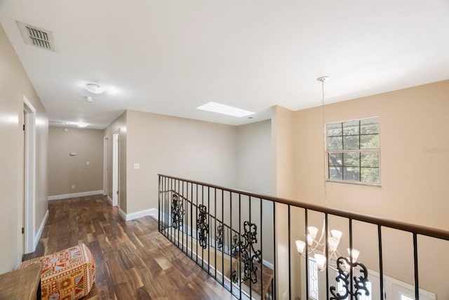 hall with dark wood-type flooring, a skylight, and a chandelier