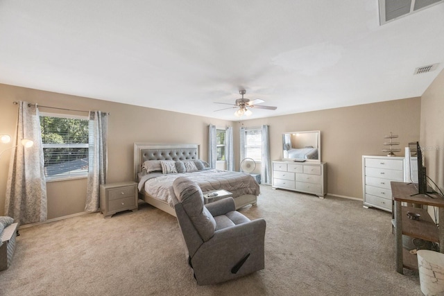 bedroom with multiple windows, ceiling fan, and light carpet