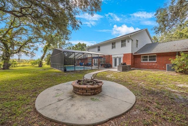 rear view of property featuring cooling unit, a lanai, a yard, a fire pit, and a patio