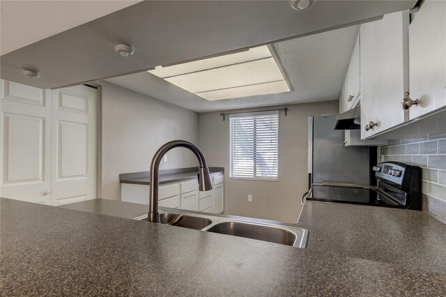 kitchen with a textured ceiling, stainless steel electric range oven, backsplash, sink, and white cabinets