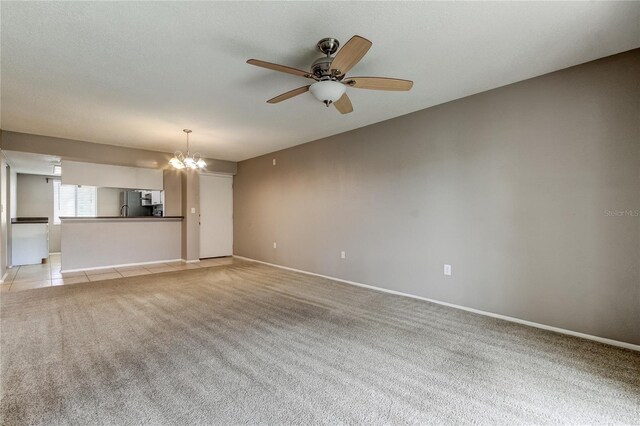 unfurnished living room featuring light colored carpet and ceiling fan with notable chandelier