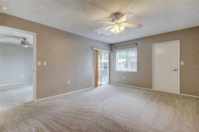 spare room with a textured ceiling, light colored carpet, and ceiling fan