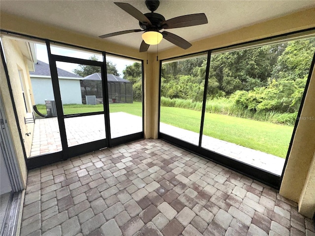 unfurnished sunroom featuring ceiling fan