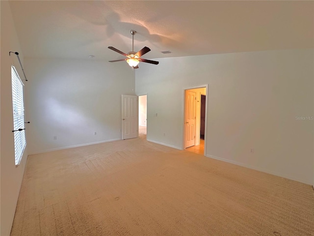 carpeted empty room with high vaulted ceiling and ceiling fan