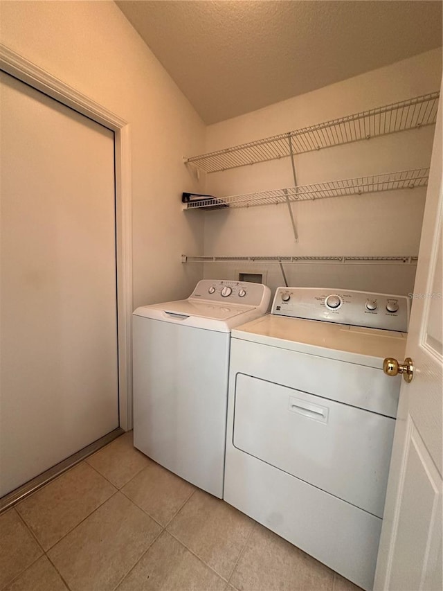 washroom featuring independent washer and dryer, a textured ceiling, and light tile patterned floors