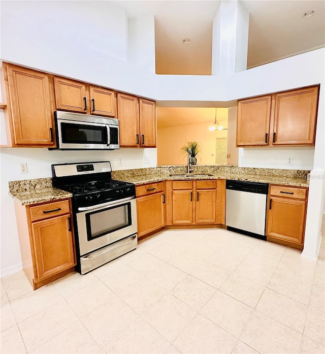 kitchen with kitchen peninsula, an inviting chandelier, sink, a towering ceiling, and stainless steel appliances