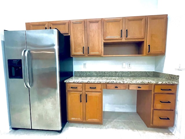 kitchen featuring stainless steel fridge, light tile patterned flooring, and light stone counters