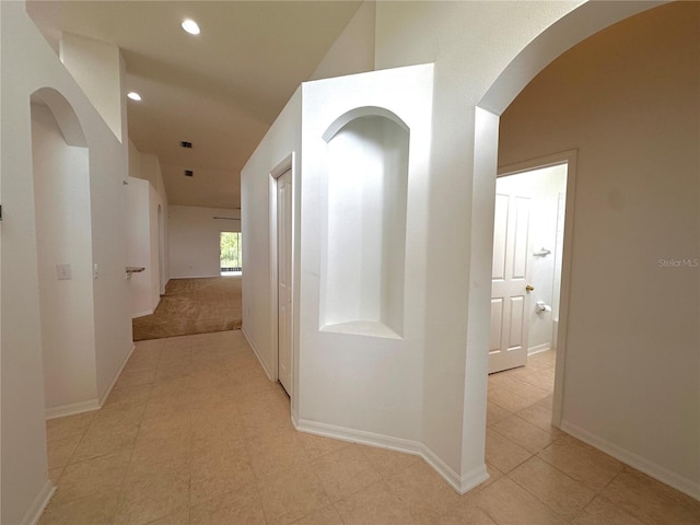 hall with arched walkways, recessed lighting, and baseboards