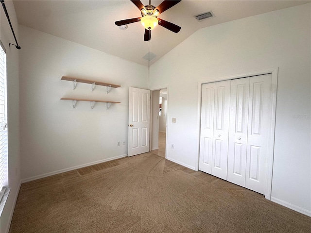 unfurnished bedroom featuring visible vents, a closet, carpet, baseboards, and vaulted ceiling