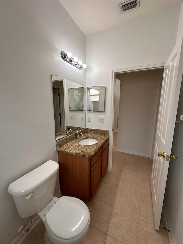 bathroom with visible vents, baseboards, toilet, vanity, and a textured ceiling