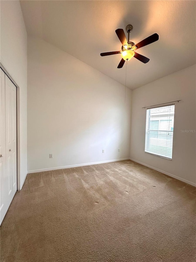 carpeted spare room featuring high vaulted ceiling, baseboards, and ceiling fan