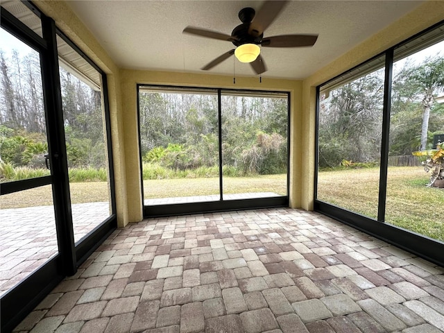 unfurnished sunroom featuring a healthy amount of sunlight and ceiling fan