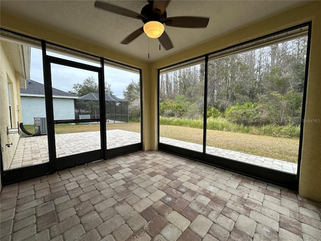 unfurnished sunroom featuring ceiling fan