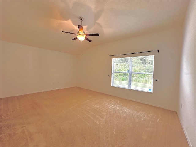 empty room with light colored carpet, baseboards, and vaulted ceiling