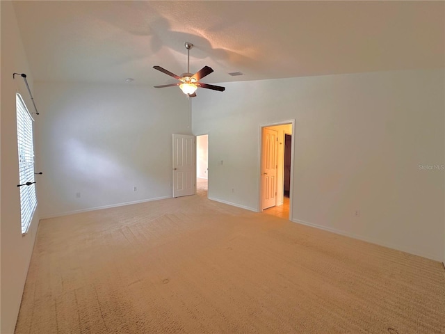 empty room featuring visible vents, baseboards, light carpet, high vaulted ceiling, and a ceiling fan