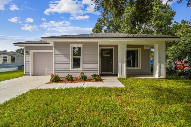 view of front of property featuring a front lawn, covered porch, and a garage