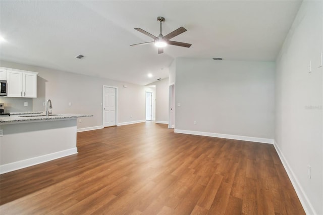 unfurnished living room featuring ceiling fan, sink, wood-type flooring, and vaulted ceiling