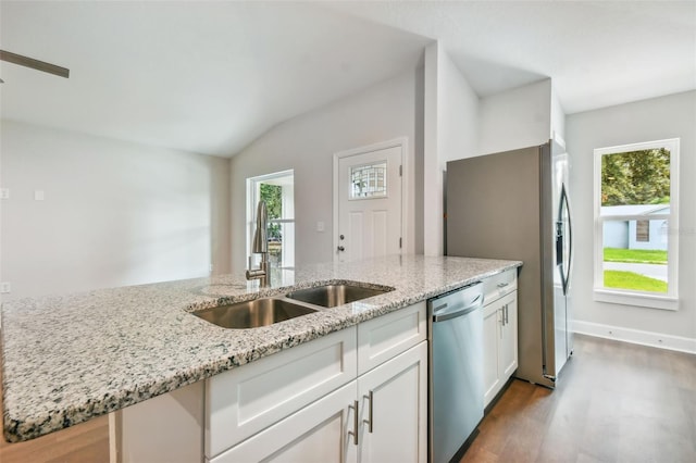 kitchen featuring light stone countertops, stainless steel appliances, white cabinetry, and a healthy amount of sunlight