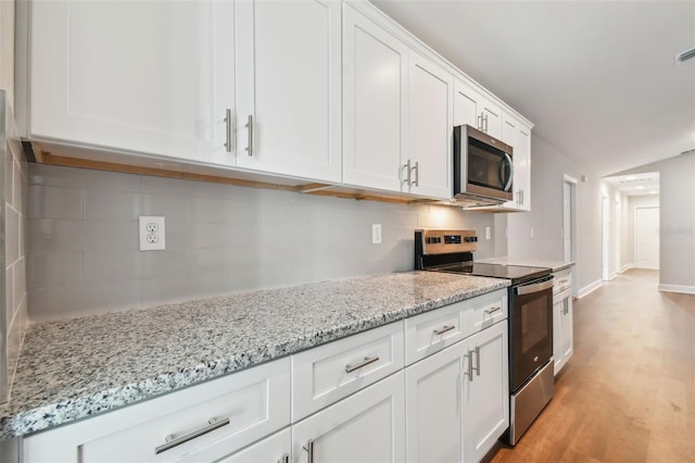 kitchen with light wood-type flooring, backsplash, stainless steel appliances, and white cabinetry