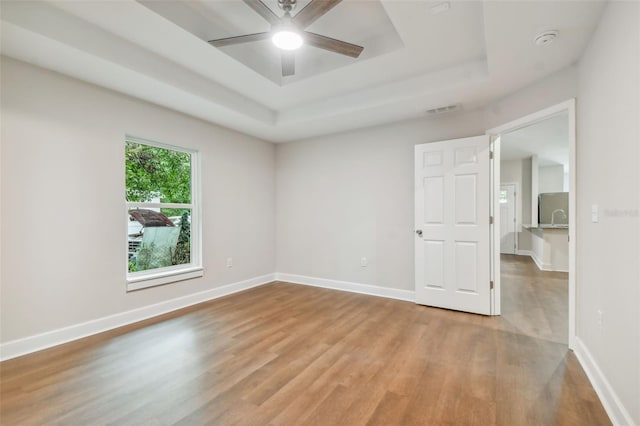 unfurnished room featuring ceiling fan, a tray ceiling, and hardwood / wood-style flooring