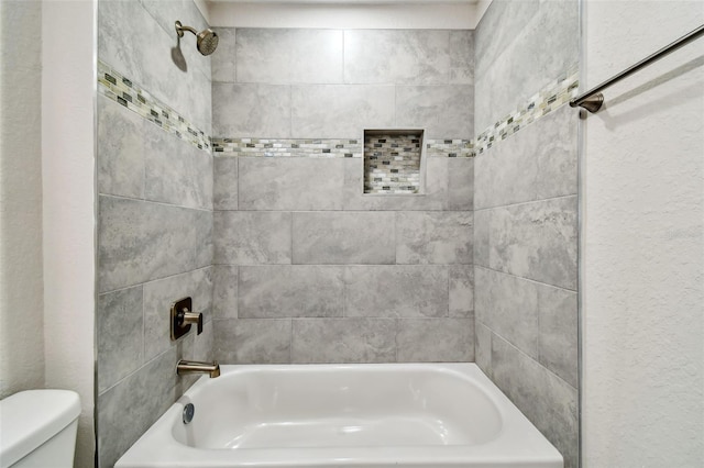 bathroom with toilet and tiled shower / bath