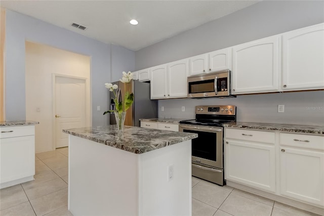 kitchen featuring a center island, white cabinets, stainless steel appliances, light tile patterned floors, and light stone countertops