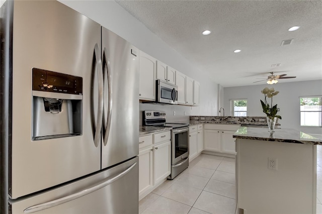 kitchen featuring ceiling fan, sink, stone countertops, white cabinetry, and appliances with stainless steel finishes