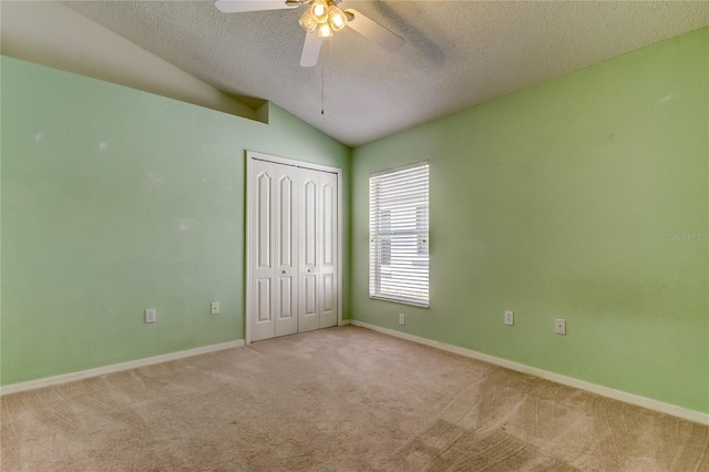 spare room featuring a textured ceiling, lofted ceiling, light carpet, and ceiling fan