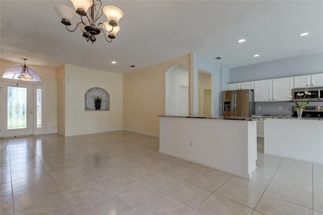 kitchen featuring dark stone counters, white cabinets, hanging light fixtures, an inviting chandelier, and stainless steel appliances