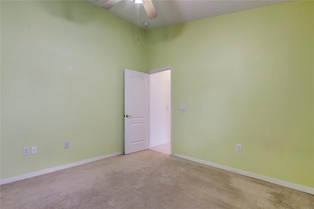 empty room with ceiling fan, light carpet, and a towering ceiling