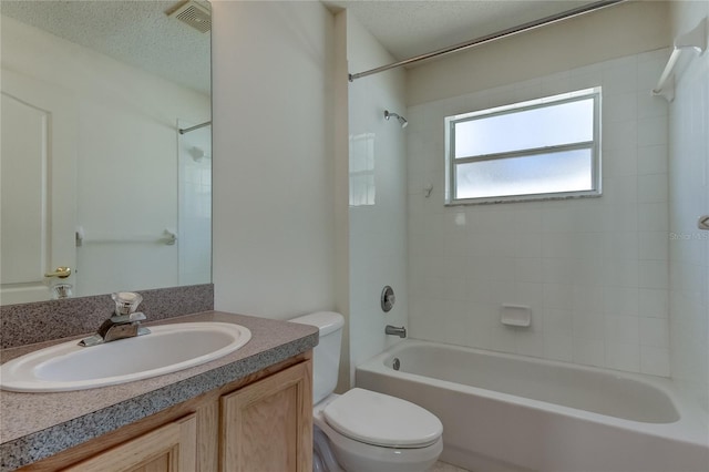 full bathroom featuring a textured ceiling, tiled shower / bath, vanity, and toilet