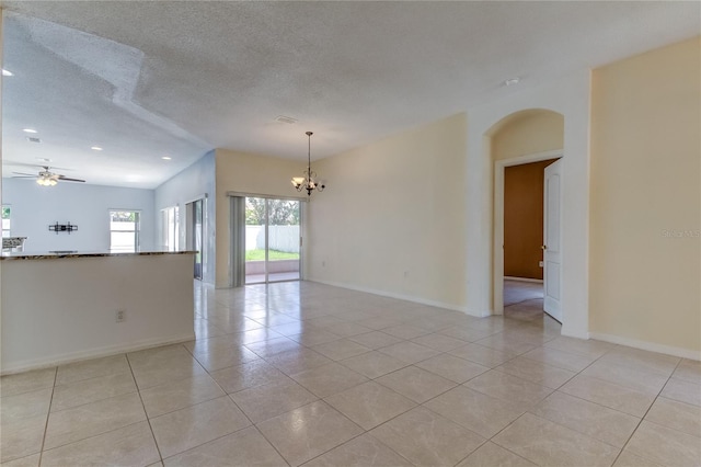 tiled spare room featuring a textured ceiling, ceiling fan with notable chandelier, and lofted ceiling