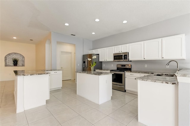 kitchen with appliances with stainless steel finishes, stone counters, a center island, and sink