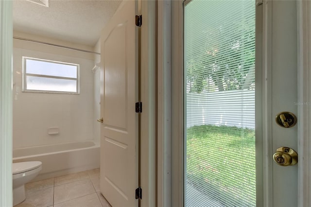 bathroom with a textured ceiling, toilet, shower / bathing tub combination, and tile patterned floors