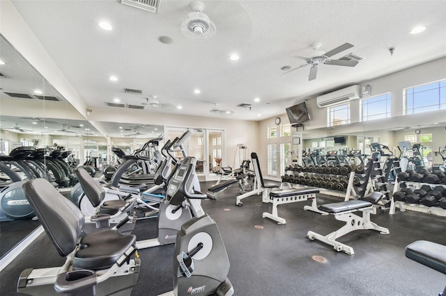 gym featuring a textured ceiling, ceiling fan, and a wall mounted AC