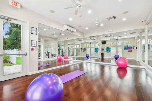 gym featuring dark hardwood / wood-style flooring, ceiling fan, and a wall mounted air conditioner