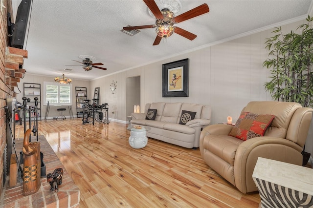 living room with light hardwood / wood-style flooring, ornamental molding, and ceiling fan with notable chandelier