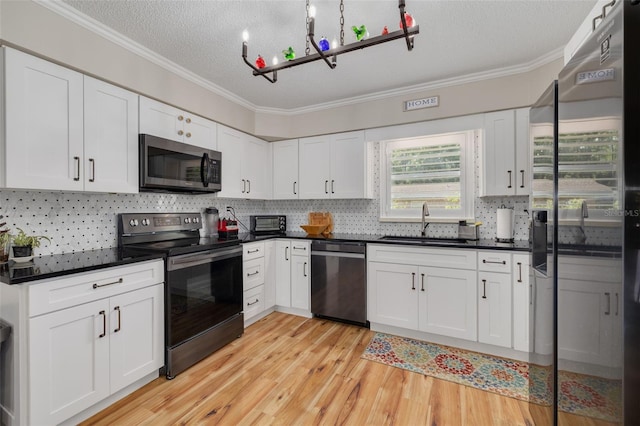 kitchen with a textured ceiling, crown molding, stainless steel appliances, sink, and light wood-type flooring