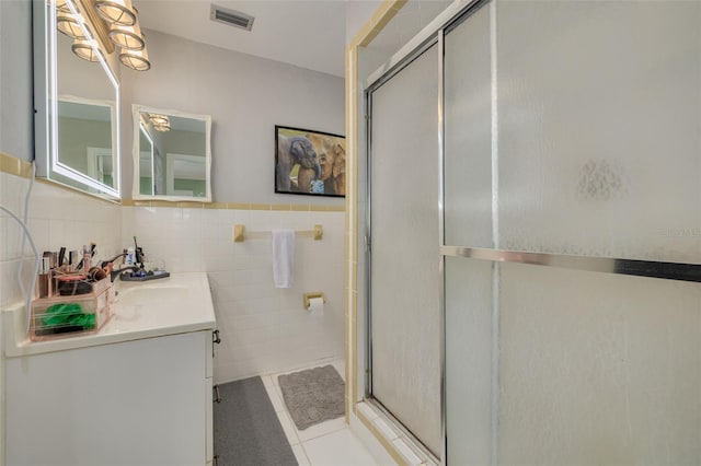 bathroom with vanity, walk in shower, tile walls, tile patterned floors, and decorative backsplash