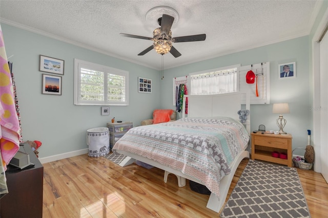 bedroom featuring light wood-type flooring, ceiling fan, ornamental molding, and a textured ceiling