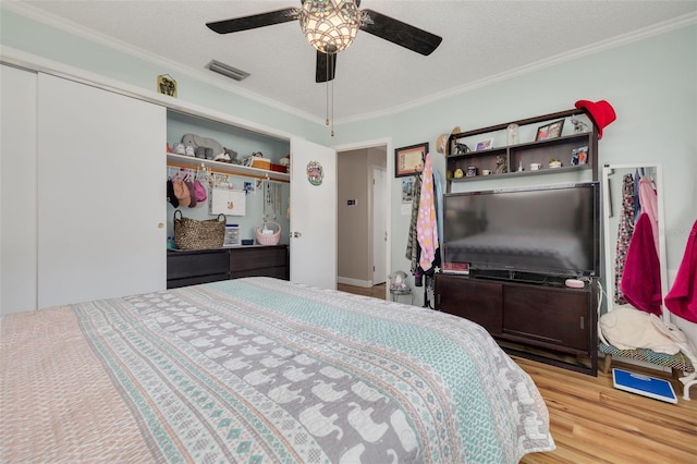 bedroom with crown molding, a textured ceiling, ceiling fan, a closet, and light hardwood / wood-style floors